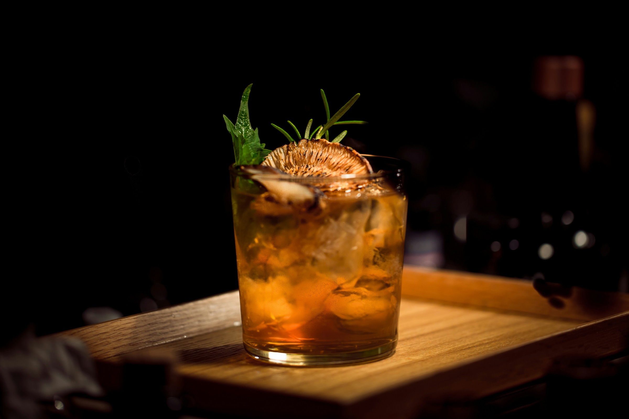 A crafted cocktail lit by a warm bar light